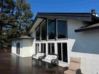 Modern home exterior featuring new black-framed windows, white stucco, and a spacious wood deck completed by Best Exteriors.